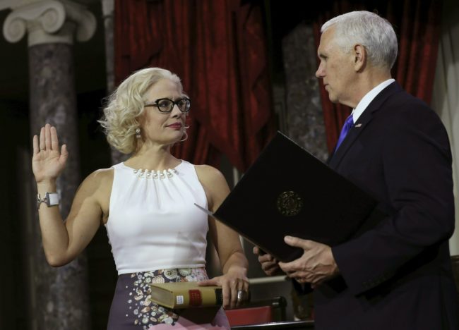 US Senator from Arizona (D) Kyrsten Sinema holds a lawbook as she is sworn in by Vice President Mike Pence (R) during the swearing-in re-enactments for recently elected senators in the Old Senate Chamber on Capitol Hill January 3, 2019