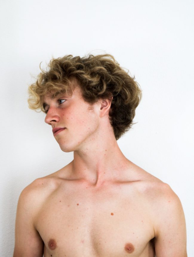A naked man against a white background, looking to the side