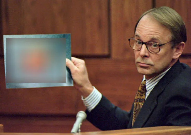 Dr. James T. Sehn holds a photo of the severed penis of John Wayne Bobbitt, which his wife had previously sliced off, during the second day of the malicious wounding trial of Lorena Bobbitt in the Prince William Circuit Court in Manassas, VA, 11 January 1994. Dr. Sehn and a team of surgeons reattached the penis in a nine-hour operation.