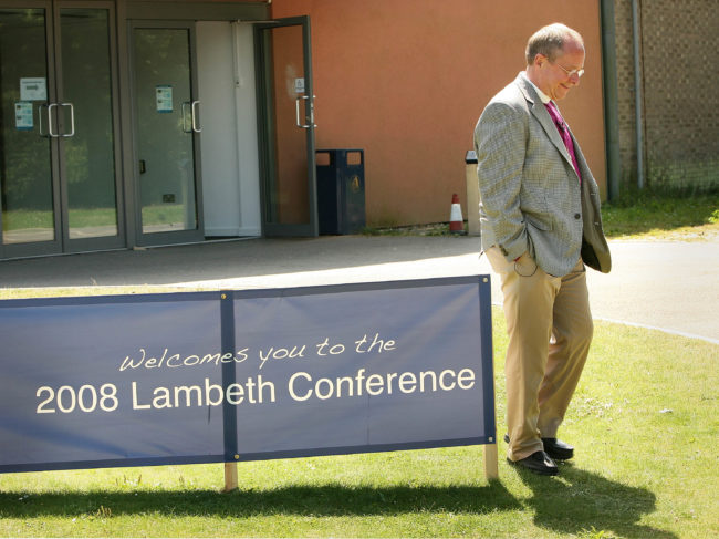 Gay American Bishop Gene Robinson walks past a sign near the market stall area of the Lambeth Conference at the University of Kent on July 21, 2008 in Canterbury, England.