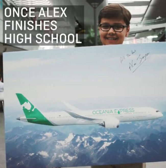 Oceania Express CEO Alex Jacquot looks at the camera while holding a rendering of his logo on a plane with the signature of Qantas CEO Alan Joyce. 
