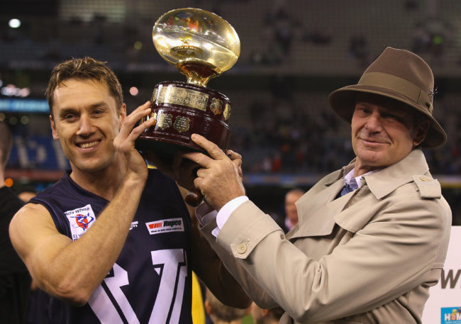 Sam Newman lifts trophy at the Etihad Stadium in Melbourne, Australia