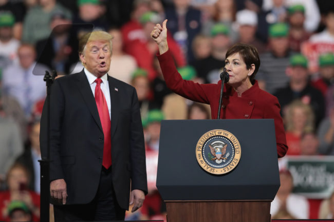 U.S. President Donald Trump listens as Iowa Gov. Kim Reynolds speaks during a campaign rally at the Mid-America Center on October 9, 2018 in Council Bluffs.