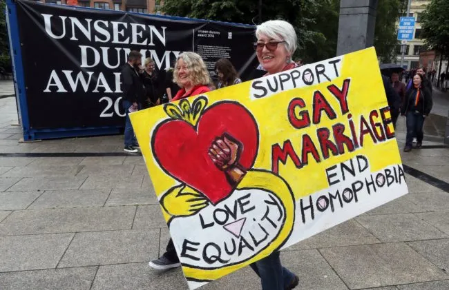 A woman holding a poster which says "support gay marriage"