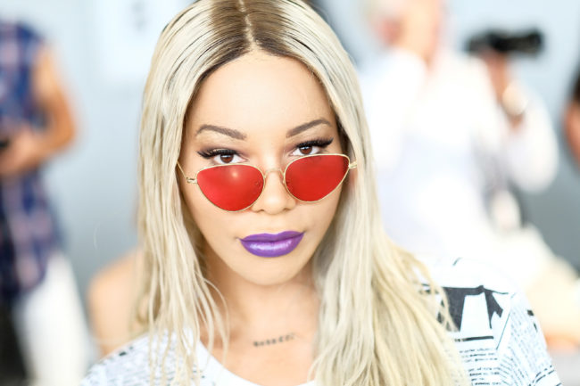 Munroe Bergdorf wearing red sunglasses and purple lipstick